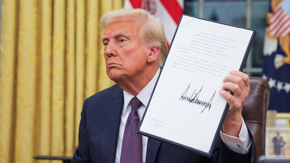 President Donald Trump holds up a signed document President Donald Trump holds up a signed document