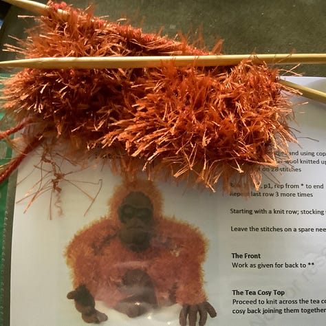 Orange fluffy fur being knitted up into two round shapes.