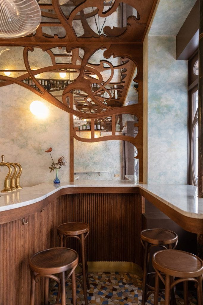 This may contain: the interior of a restaurant with wooden stools and tables in it, along with an intricately designed ceiling This may contain: the interior of a restaurant with wooden stools and tables in it, along with an intricately designed ceiling