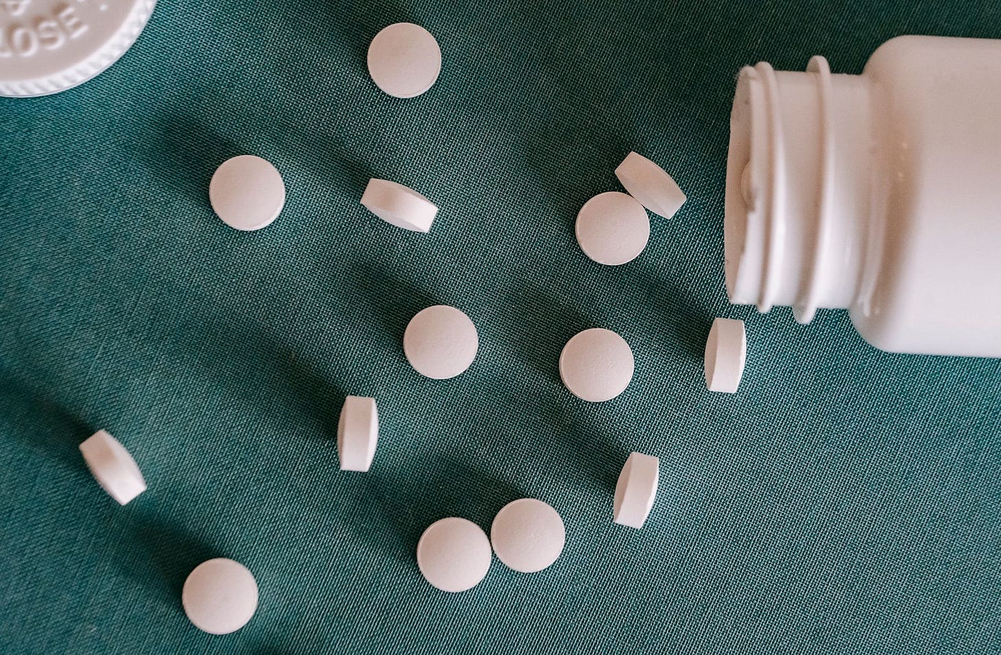 Photo by Alex Green on Pexels Top view of similar small round white pills spilled from plastic container on green surface (stock photo)