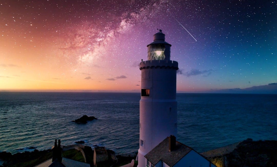 white and black lighthouse near body of water during night time white and black lighthouse near body of water during night time