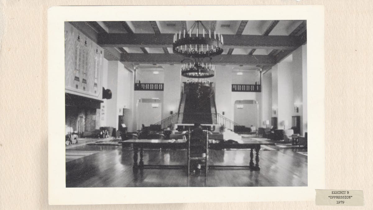 Black-and-white still from The Shining (1980) showing the empty lobby of the Overlook Hotel, emphasizing isolation and psychological tension.