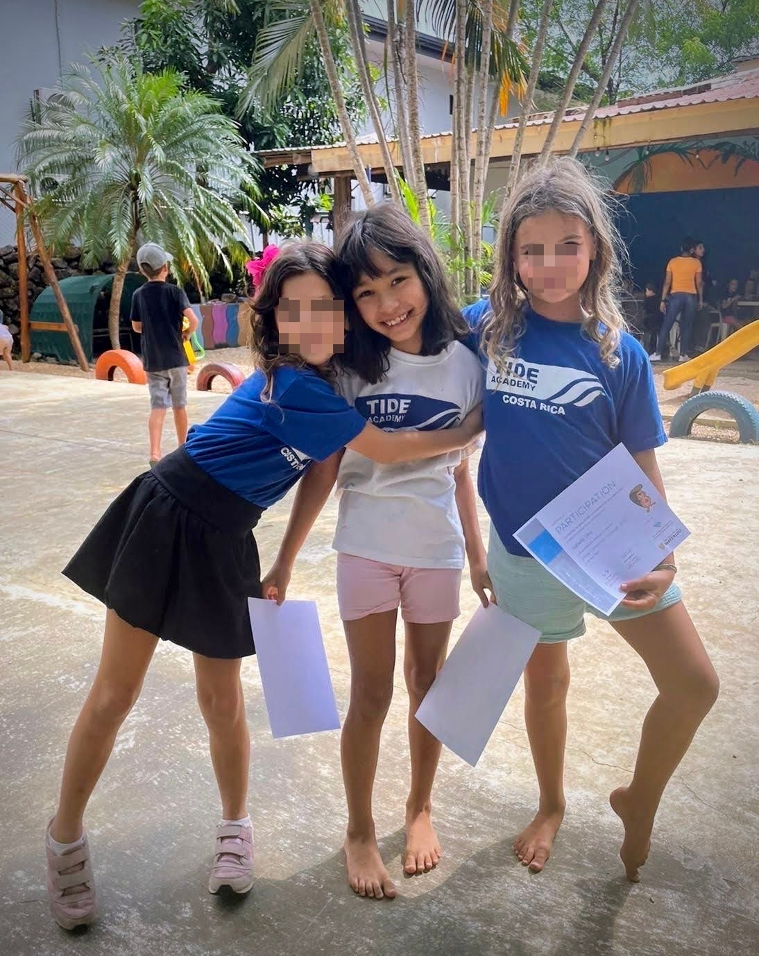 three girls hugging on playground.