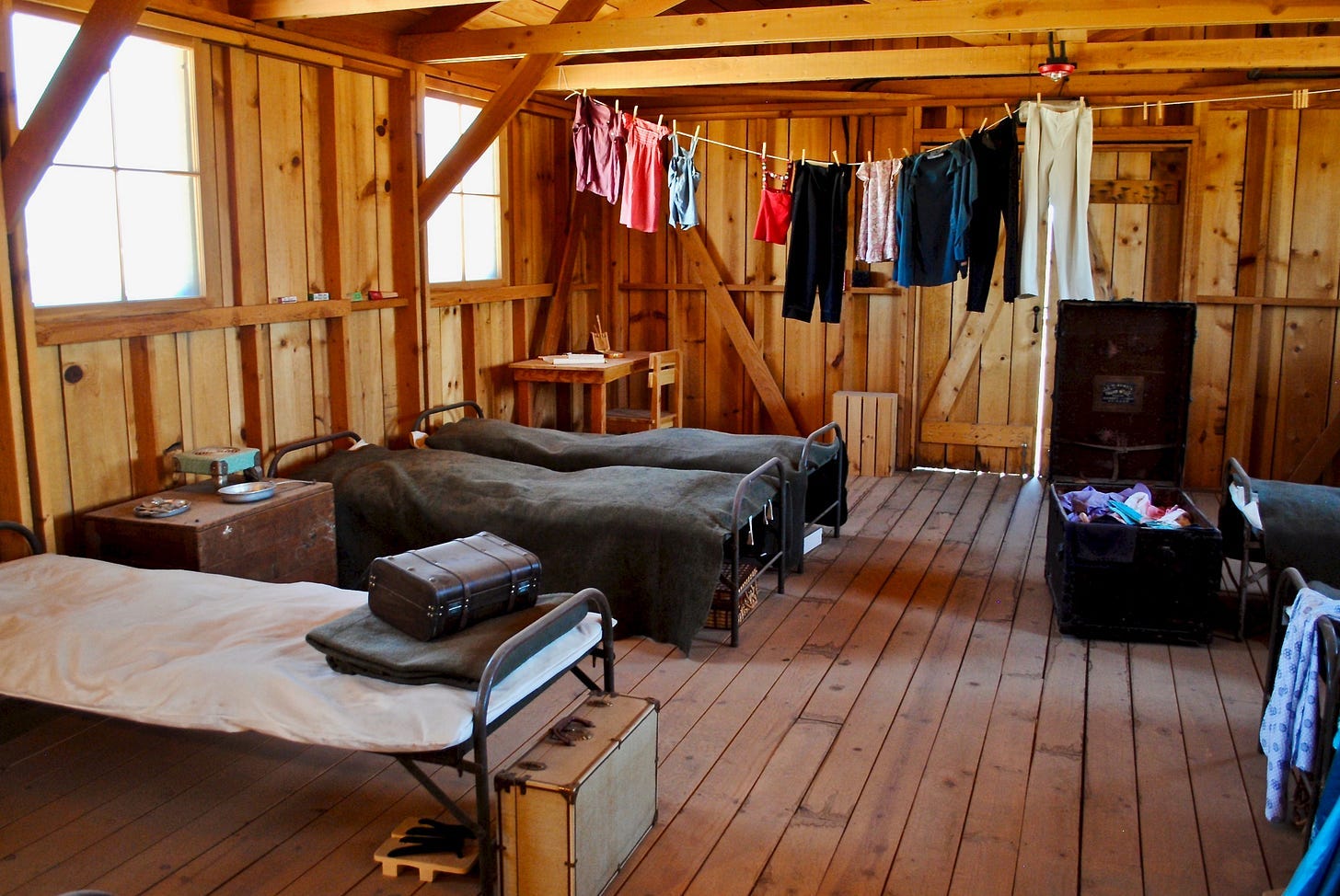 A room with beds and clothes from a rope

AI-generated content may be incorrect.