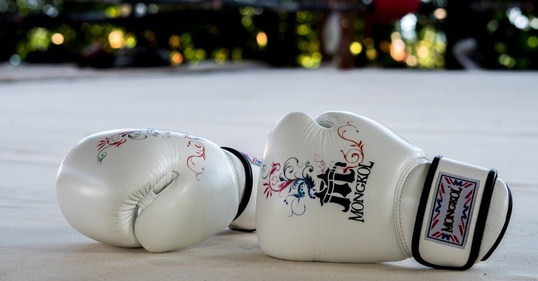 A pair of white boxing gloves laying on the ground