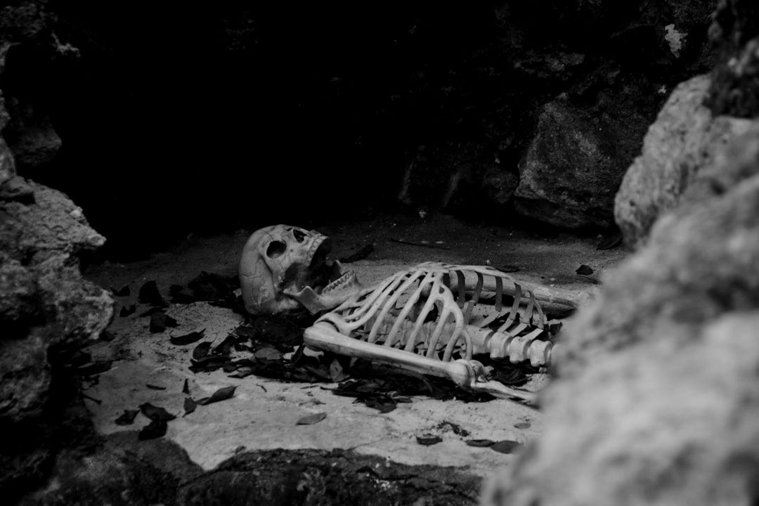 a skeleton laying on the ground in a cave