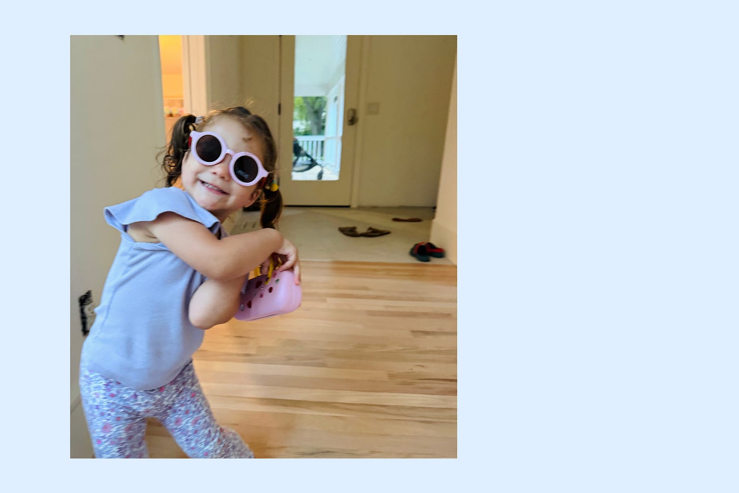 Elodie, two years old, standing in the hallway at home wearing sunglasses and carrying a small purse, thrilled with herself Elodie, two years old, standing in the hallway at home wearing sunglasses and carrying a small purse, thrilled with herself
