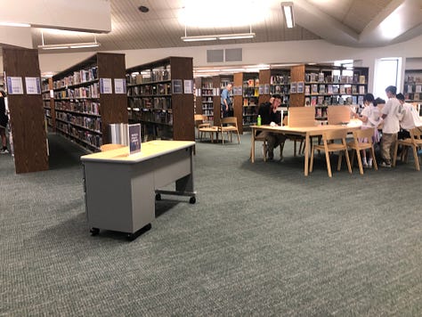 People in library borrowing books, browsing, reading 