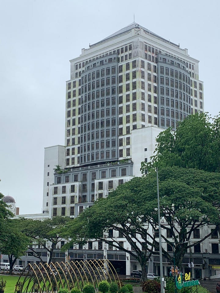 the exterior of an older hotel building versus the interior of a hotel with cakes and the backs of 2 children choosing something to eat.