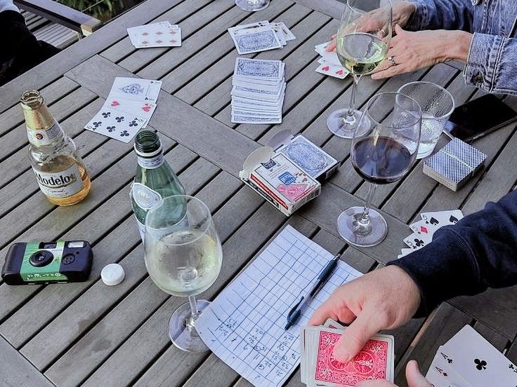 This may contain: two people playing cards at an outdoor table