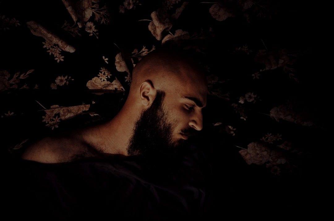 A man with a beard laying down in the dark A man with a beard laying down in the dark