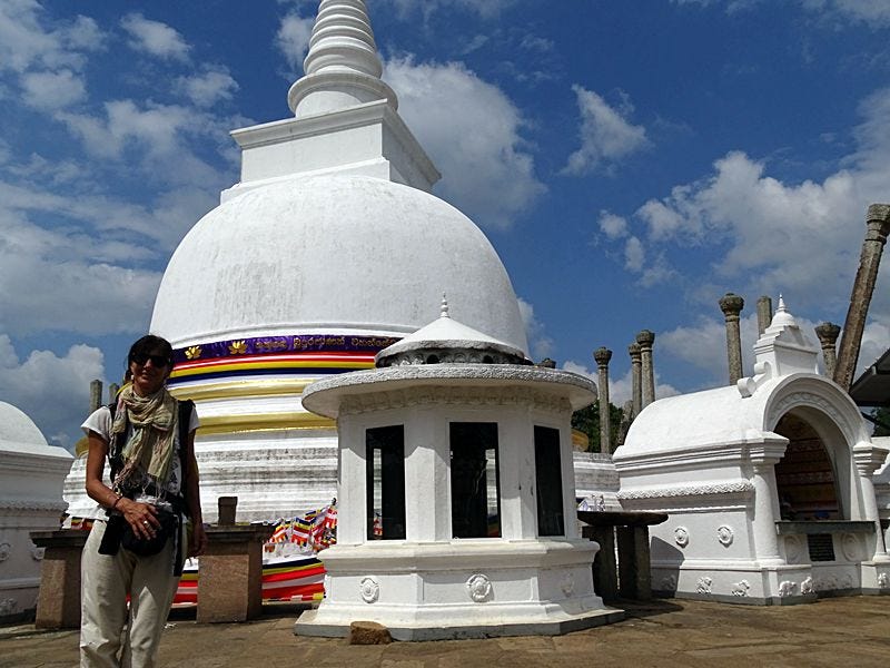 Woman walking barefoot near a large ancient stupa