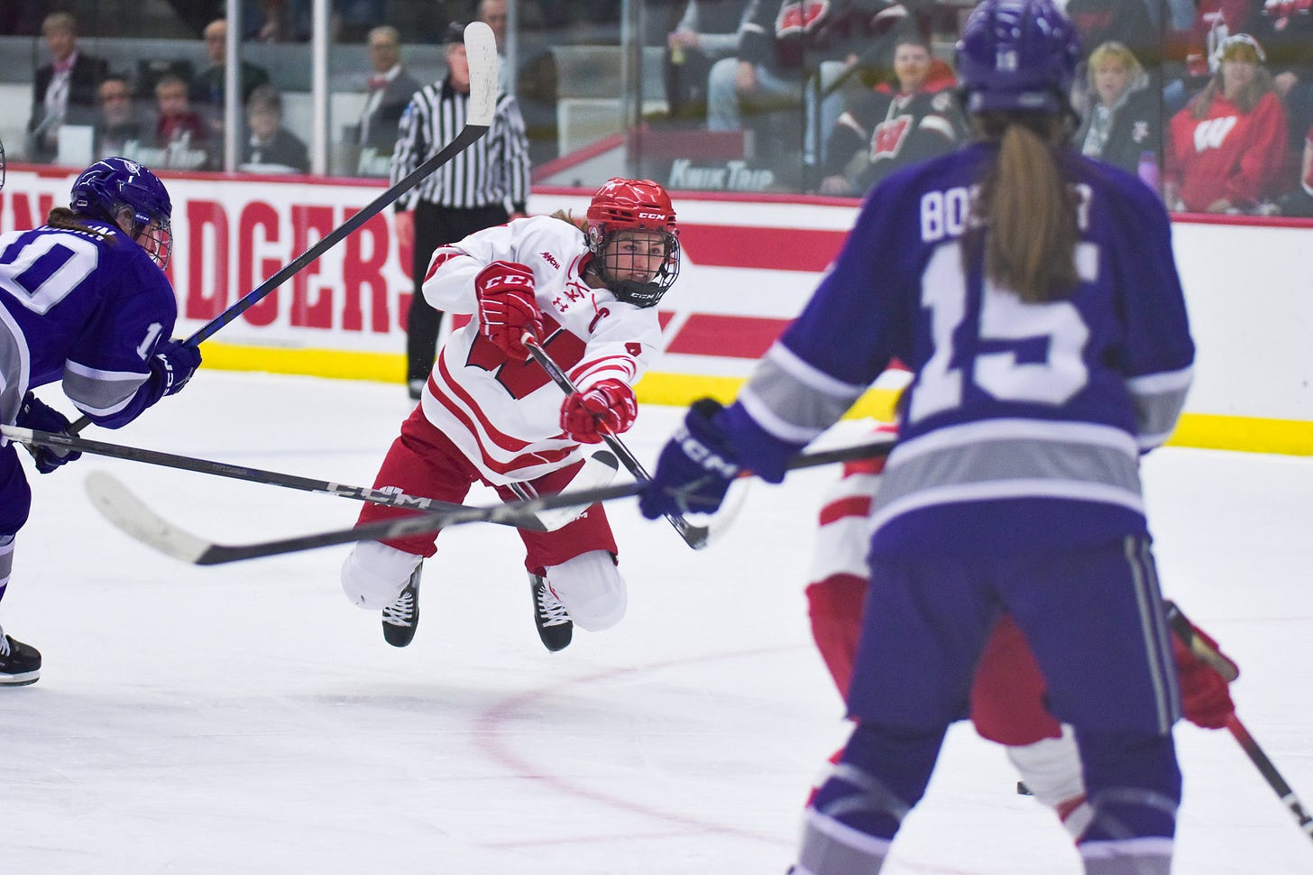 Badger women's hockey defender Caroline Harvey leaving her feet and shooting a puck toward the net