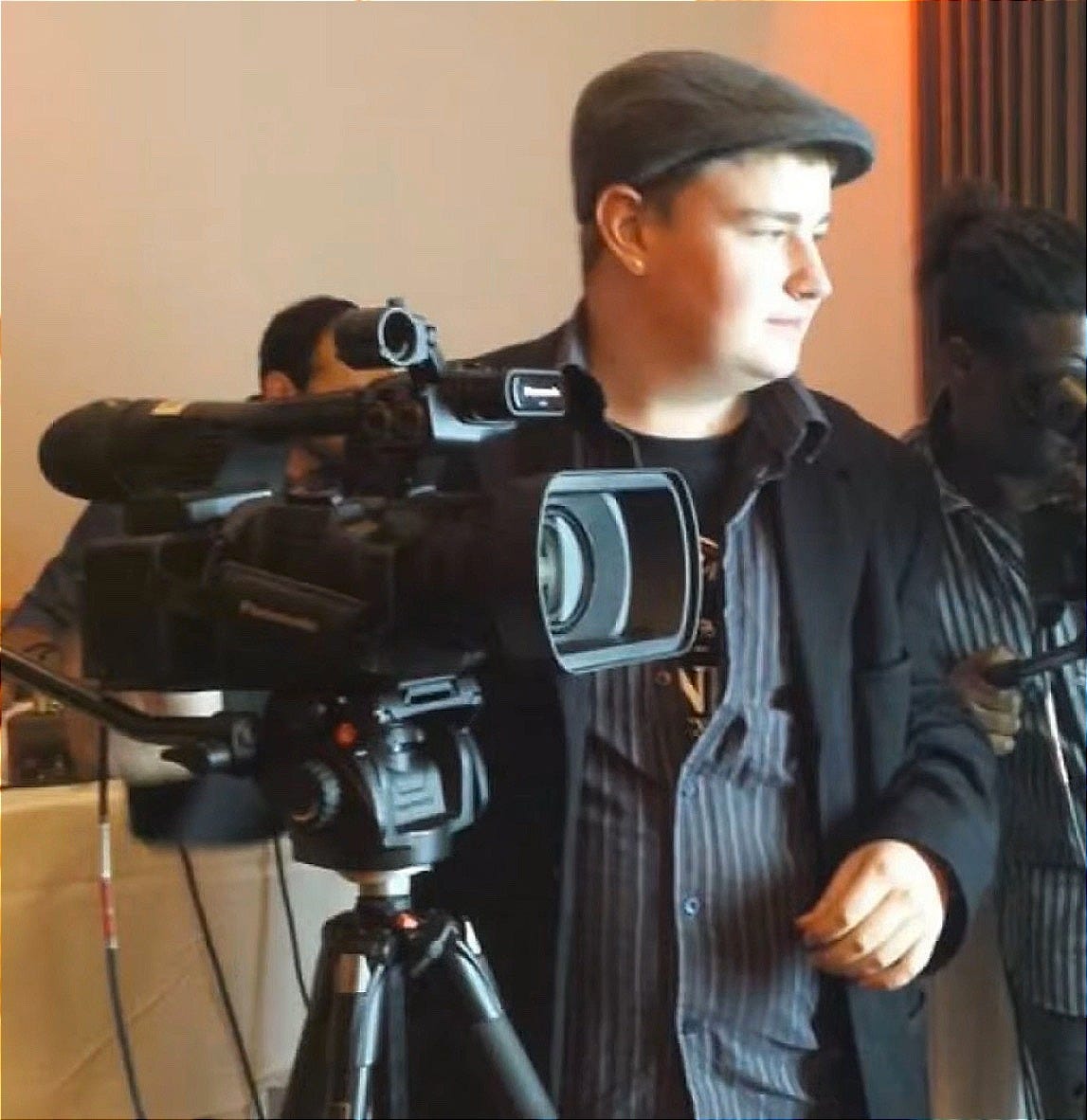 Young man wearing hat working with a film camera.