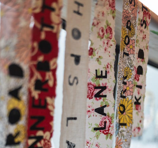 Strips of patterned material with words on hanging vertically against a window