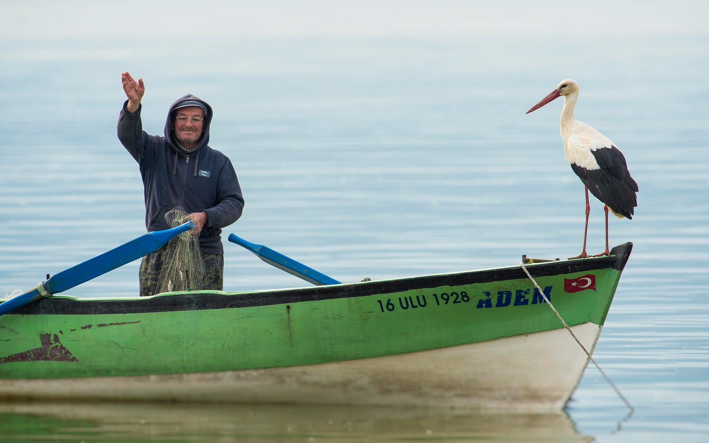 a fisherman and a stork standing on a boat