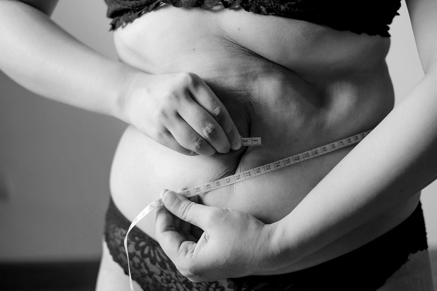 A person measuring their waist after undergoing a slimming treatment. A person measuring their waist after undergoing a slimming treatment.