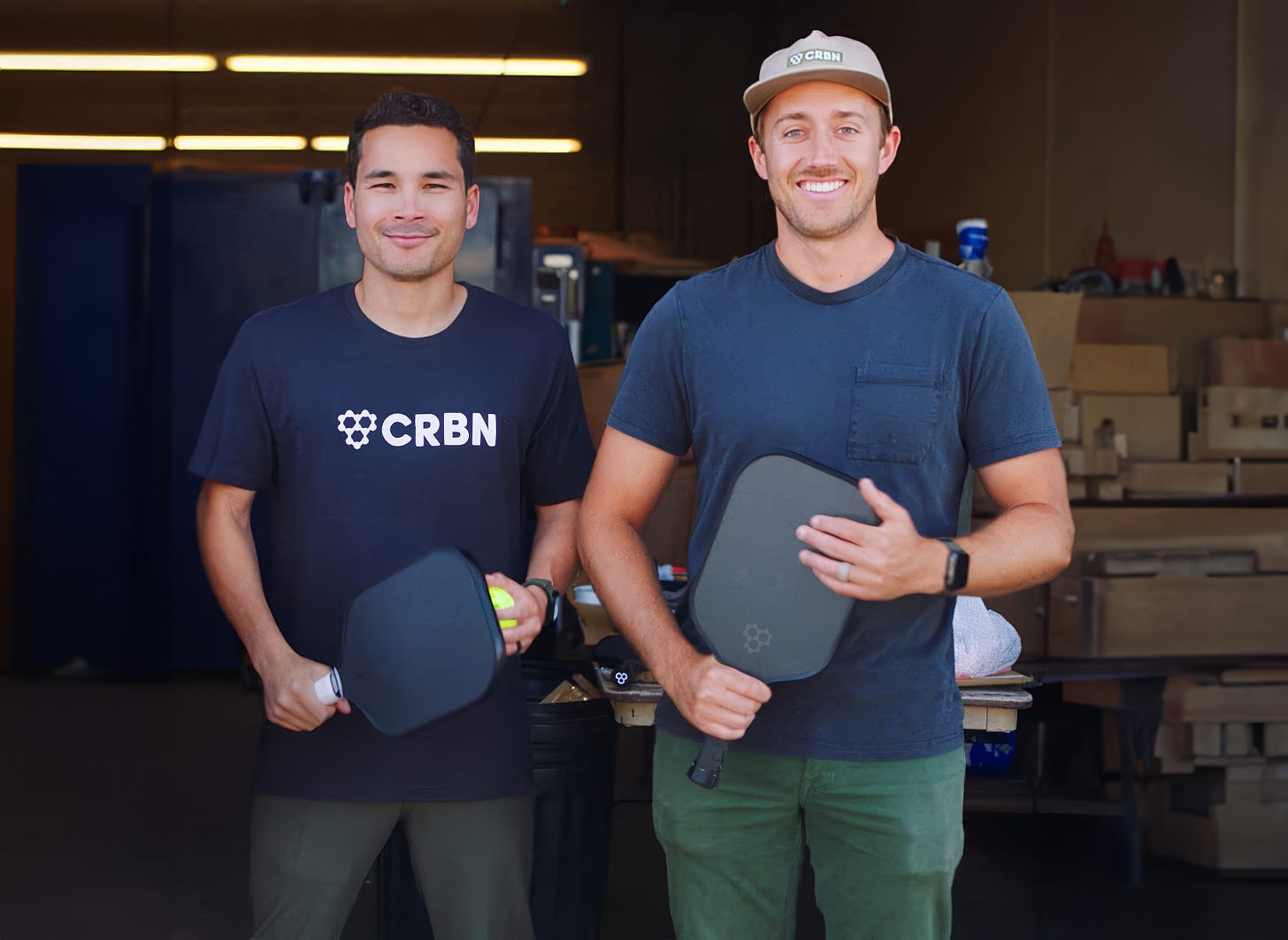 An image of CRBN Pickleball co-founders Kyle Goguen and Garrett Gosselin standing side by side, holding pickleball paddles