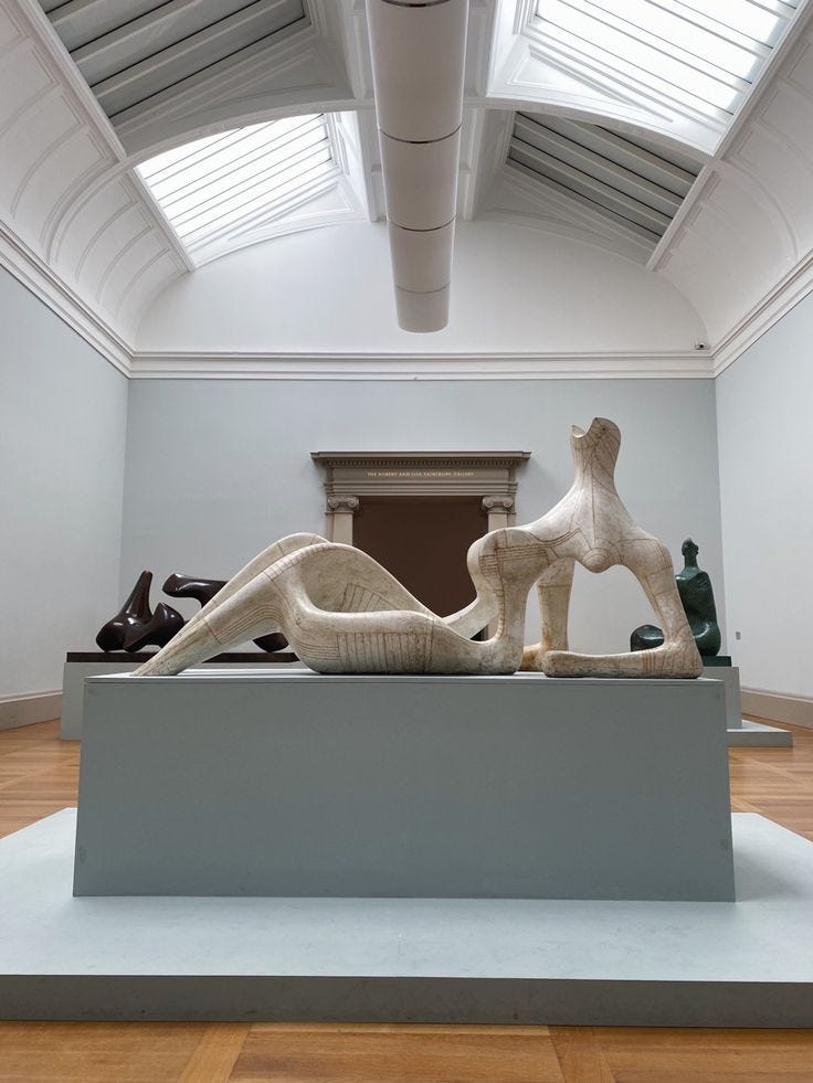 This may contain: an art gallery with sculptures on display in front of a skylight and wooden floors