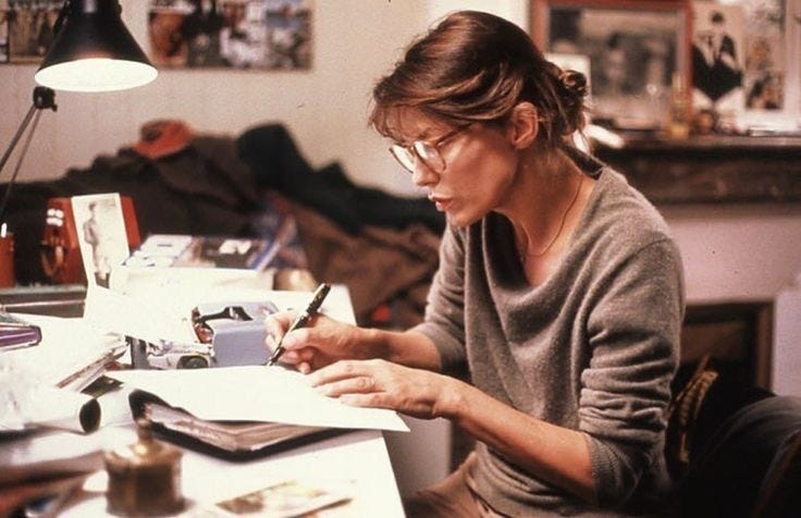 This may contain: a woman sitting at a desk writing on a piece of paper with a lamp in the background