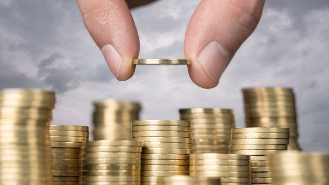 two fingers adding a coin to one pile of coins among many
