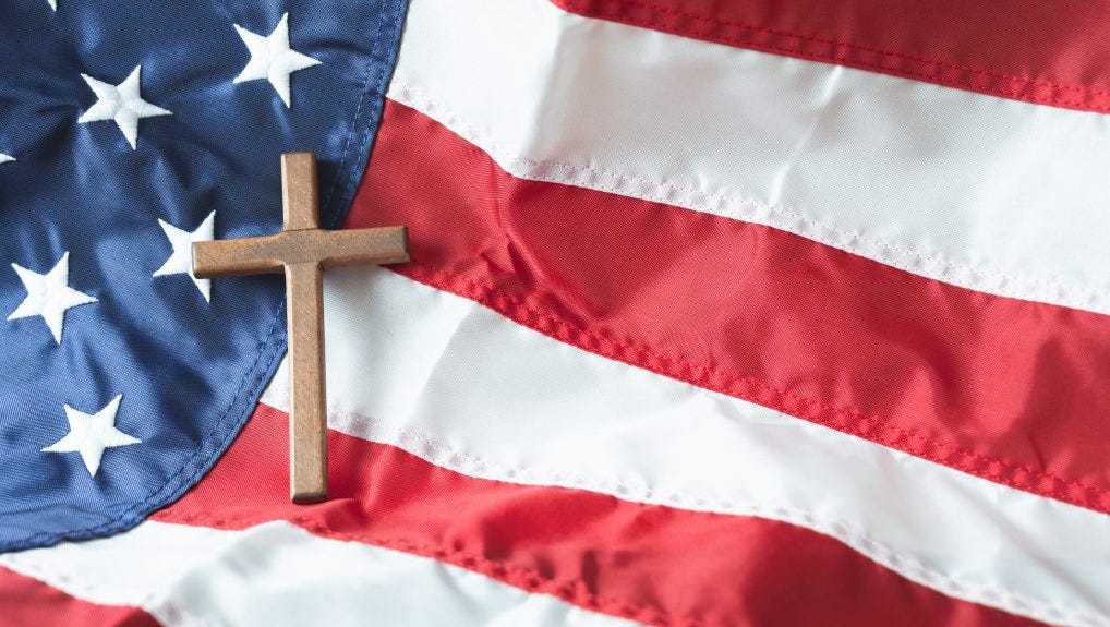 A wooden cross sits on top of an American flag. A wooden cross sits on top of an American flag.
