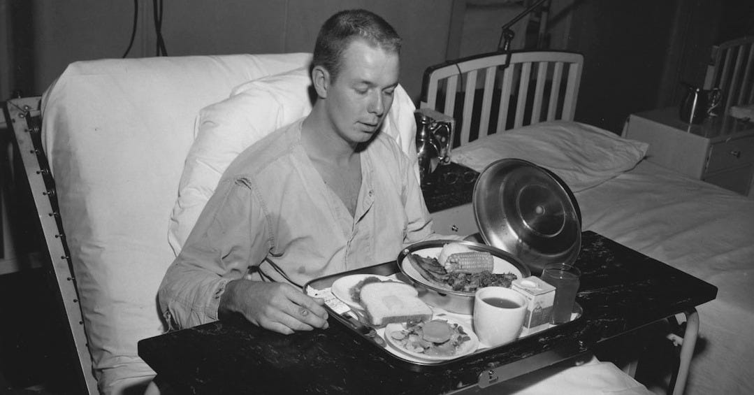 A man in a hospital bed eating a meal A man in a hospital bed eating a meal