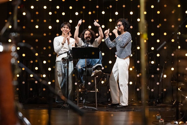 Three Asian men in music studio with lights behind them