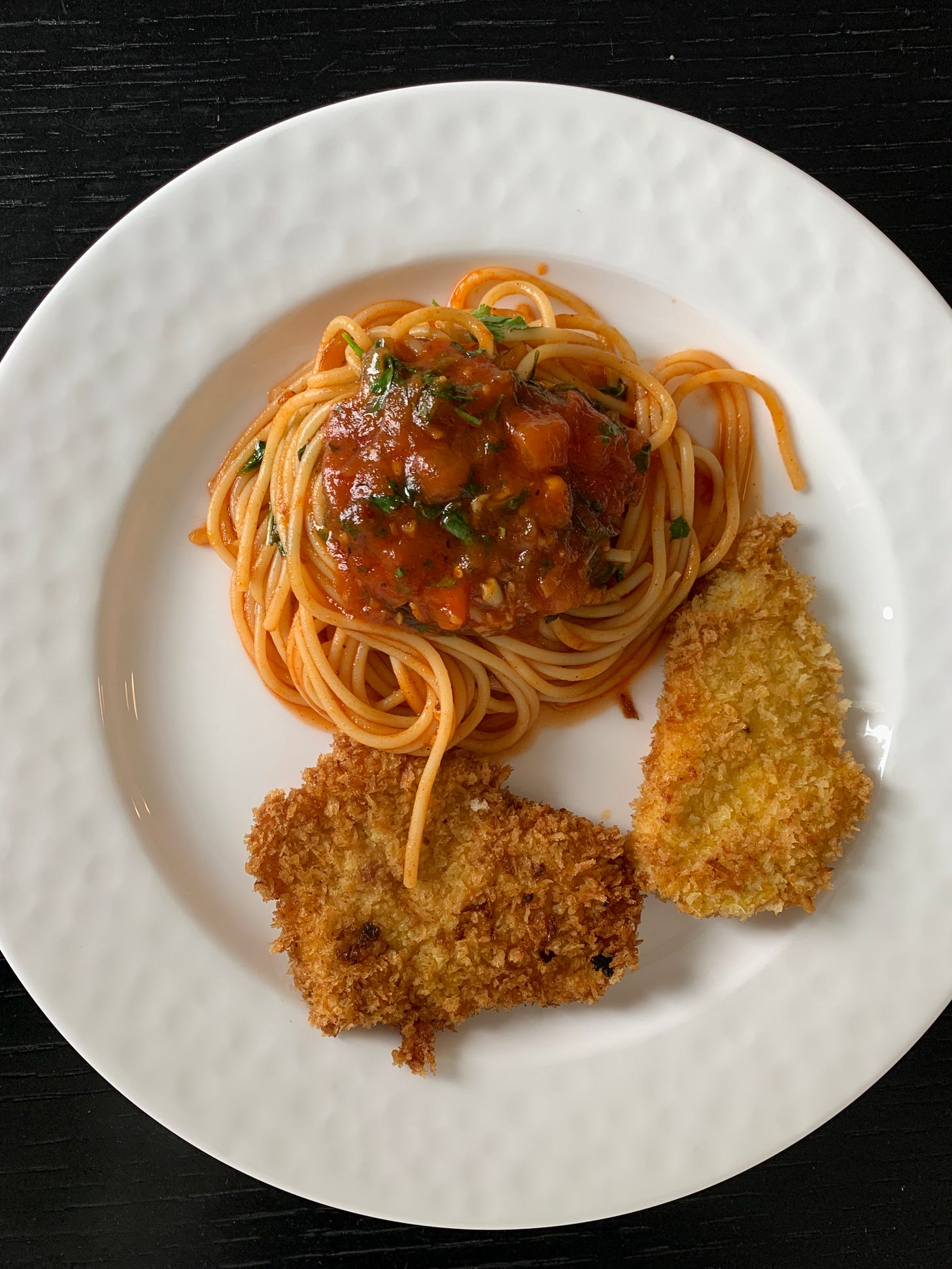 A hearty plate of spaghetti topped with fresh homemade tomato sauce, served alongside crispy schnitzel. Photographed by Liat Portal for Foodie Disorder, highlighting the comfort and warmth of a classic homemade meal.