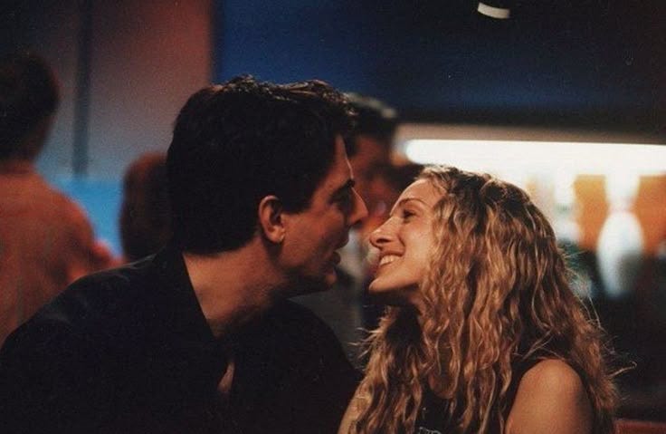 This may contain: a man and woman sitting next to each other in front of a crowd at night