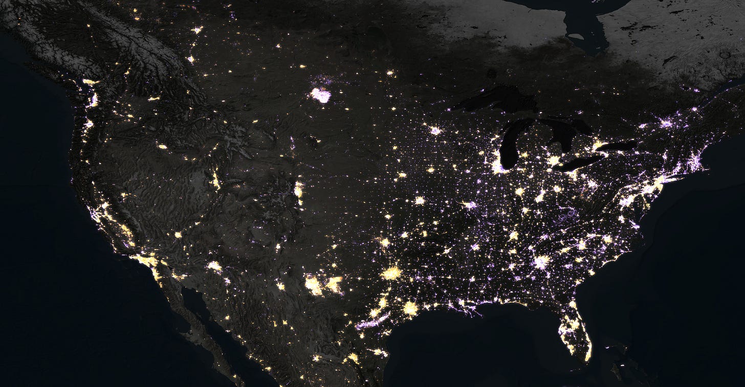 Satellite view of North America at night showing illuminated cities and populated areas, with concentrated lights in the eastern United States and scattered lights in the west.