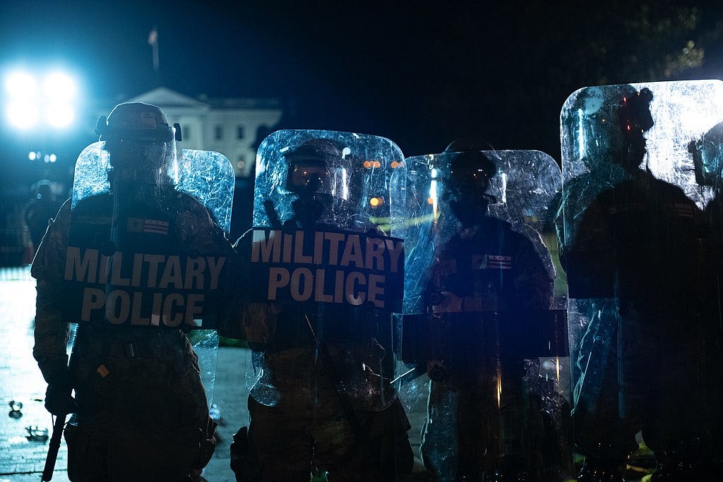 Four MPs with transparent plastic shields stand between demonstrators and the White House on May 30, 2020.