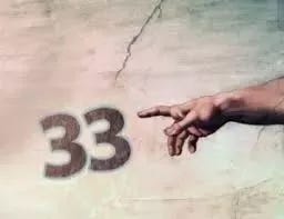 A hand with fingers extended points toward the large numeral 33 displayed on a textured wall with visible cracks.