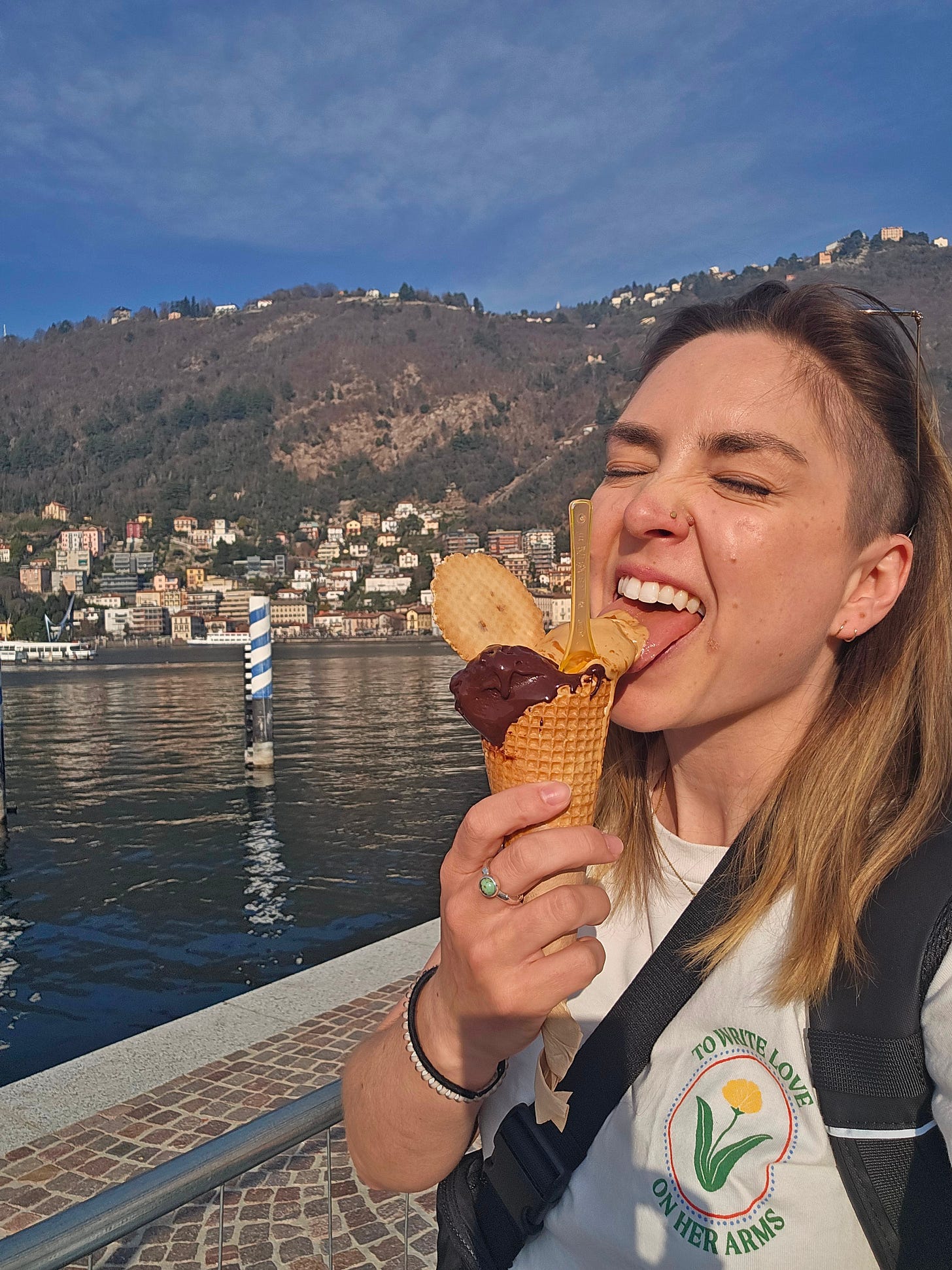 Cassidy standing in front of Lake Como, licking a double scoop cone of gelato. Cassidy standing in front of Lake Como, licking a double scoop cone of gelato.