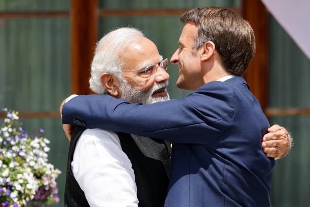 India's Prime Minister Narendra Modi and France's President Emmanuel Macron embrace as they arrive to attend the outreach program on June 27, 2022 at...
