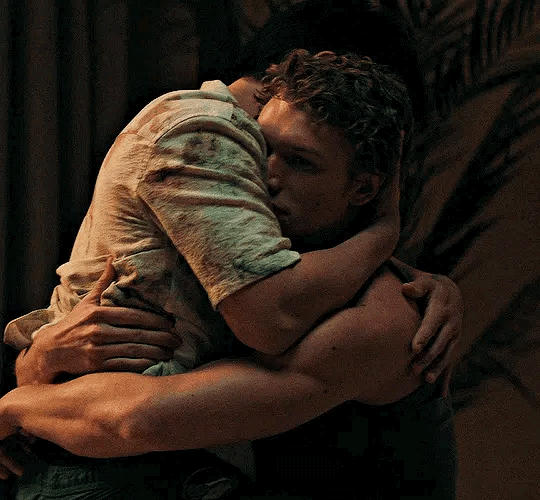 This may contain: two men hugging each other in the dark