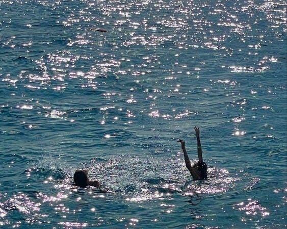 This may contain: two people swimming in the ocean with their hands up and one person diving into the water