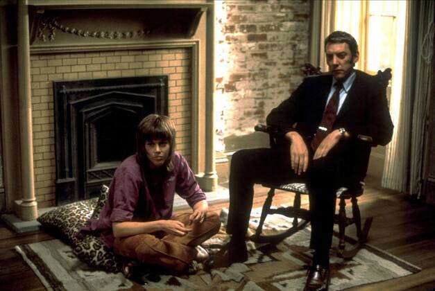 Bree Daniels (Jane Fonda) sitting on a rug and John Klute (Donald Sutherland) on a chair in Klute (1973)