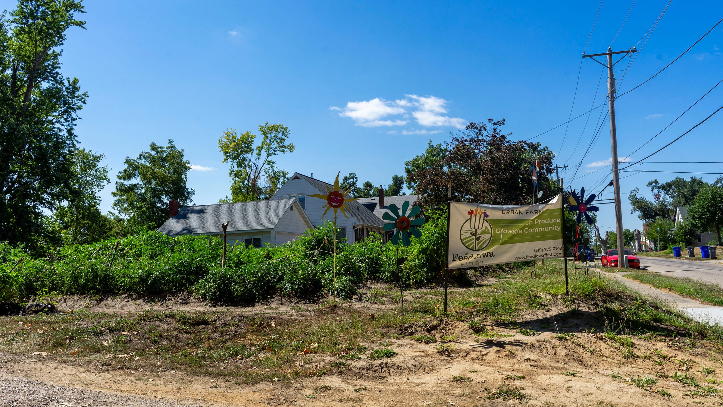 A sign in front of an urban farm site along a dirt road.