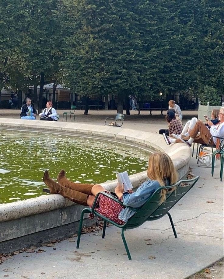 This may contain: a woman sitting in a chair next to a fountain