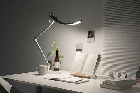 a desk with a lamp and a cup of coffee