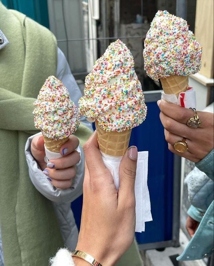 This may contain: three ice cream cones with sprinkles on them being held by two women This may contain: three ice cream cones with sprinkles on them being held by two women