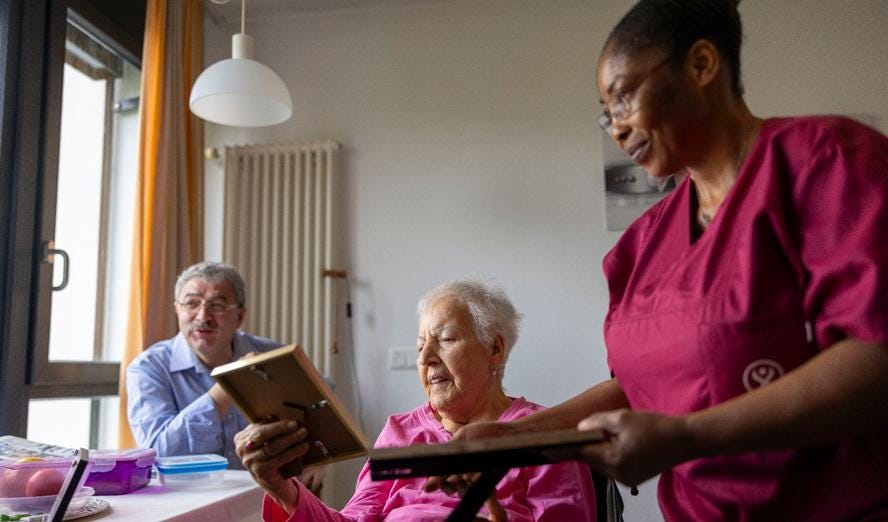 Retiree Gülen Demirkale shows nurse Doreen Ohemeng, who is from Ghana, photos of her family at Victor-Gollancz-Haus in Frankfurt, Germany, October 7, 2023