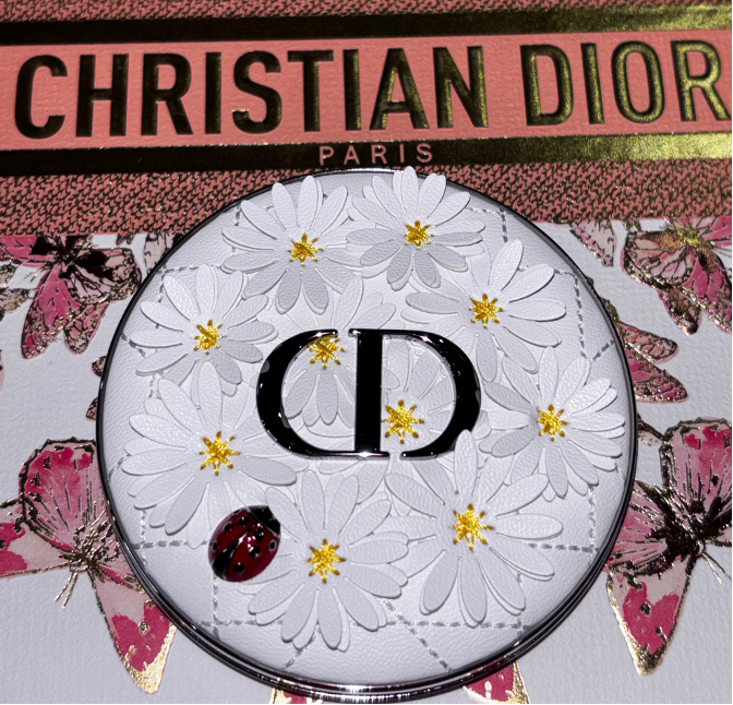 The collectible Dior Beauty Dioriviera 2026 compact featuring a raised white daisy design and a tiny ladybug motif, a nod to Christian Dior’s symbols of luck, as featured on The Beauty Ed®.