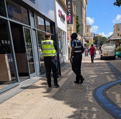 A uniformed Bristol BID Ranger with rigid handcuffs on his belt patrolling Broadmead, Bristol city centre, alongside an officer in SWL Security hi-vis. The Almighty Gob, www.thealmightygob.com