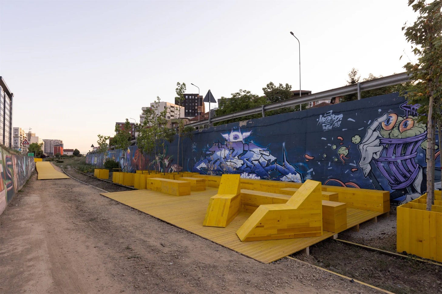 Installazione urbana a Pristina. Un vecchio binario è stato riqualificato con sedute e piante. Ogni pezzo dell'installazione urbana è giallo. Installazione urbana a Pristina. Un vecchio binario è stato riqualificato con sedute e piante. Ogni pezzo dell'installazione urbana è giallo.