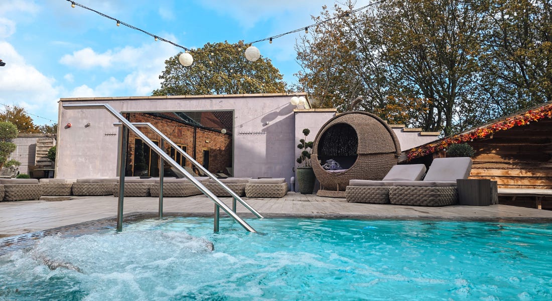 A pool with two buildings and lodges behind it A pool with two buildings and lodges behind it