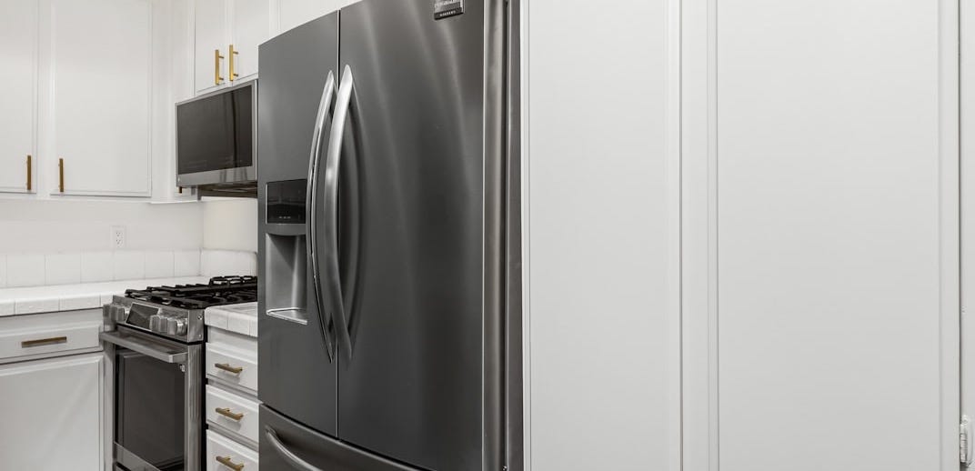 A kitchen with white cabinets and stainless steel appliances