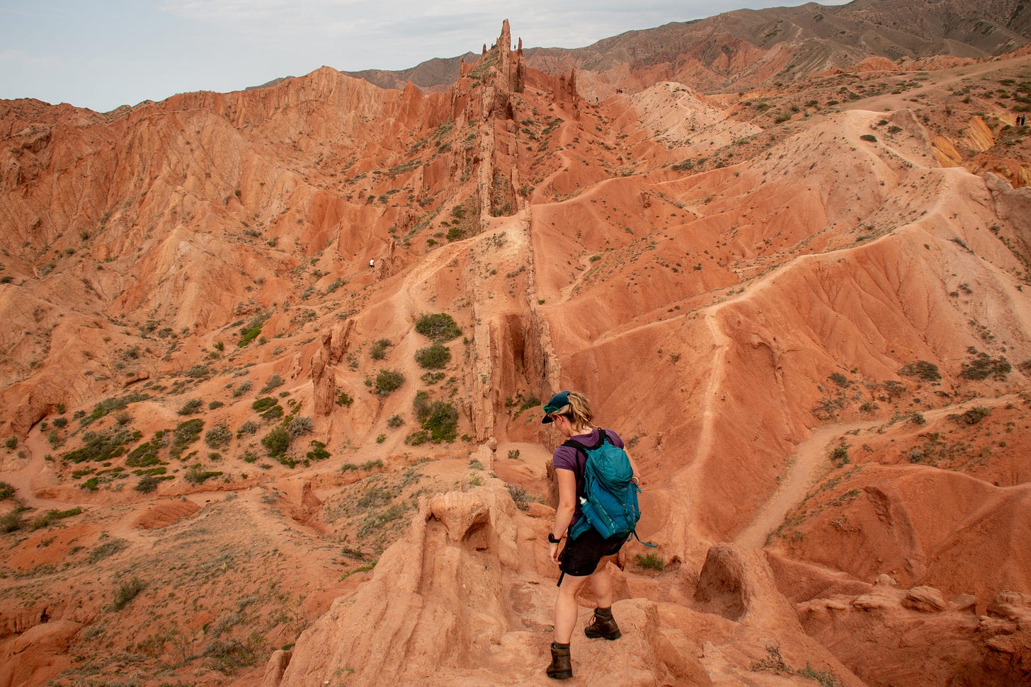 Woman stands on a ridge near the entrance to Skazka Canyon