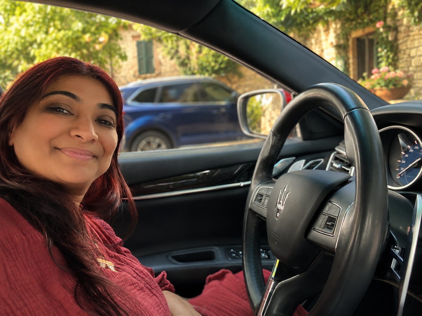 Self-portrait of Chef Daljeet seated behind the steering wheel of her car, smiling gently in warm sunlight filtering through the windows. Self-portrait of Chef Daljeet seated behind the steering wheel of her car, smiling gently in warm sunlight filtering through the windows.